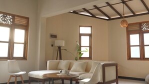 A spacious living room with a high ceiling, a sofa set, a coffee table, and a floor lamp.