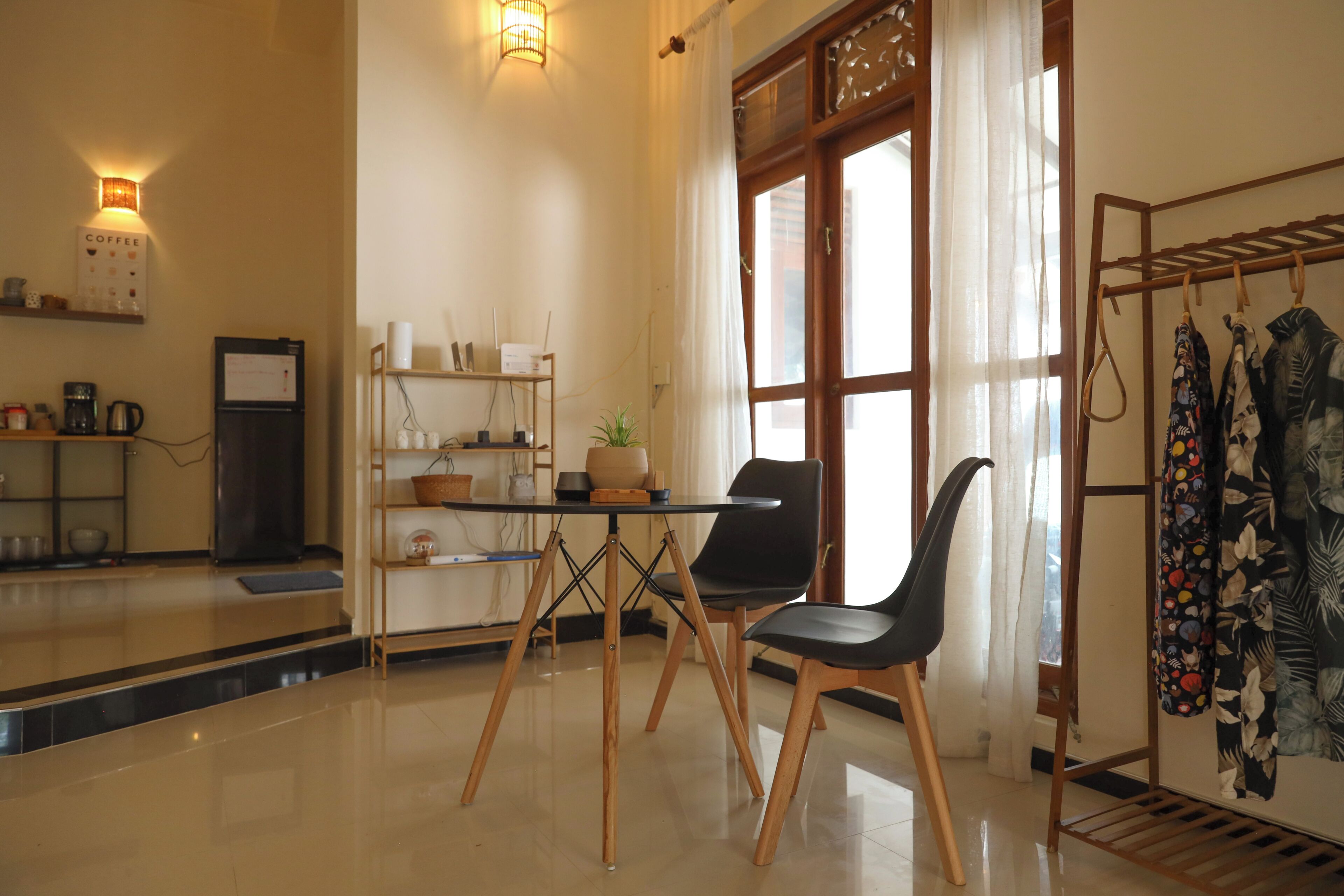 A modern kitchen with a dining area, including a table with chairs, a coffee machine, and a refrigerator.