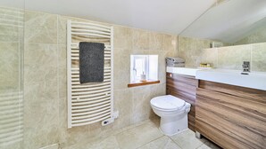A bathroom with a toilet, a towel rack, a mirror, and a vanity with a sink.
