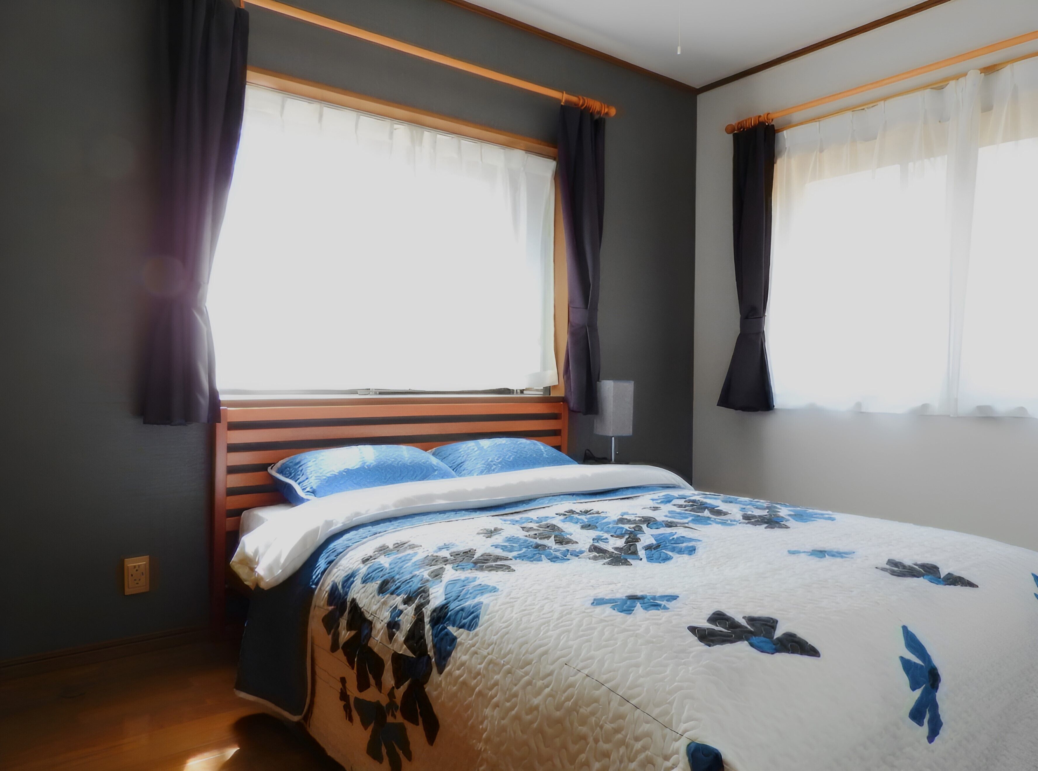 Un dormitorio con cama, cortinas, una mesita de noche y un tocador.