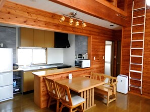 A compact kitchen with wooden cabinetry, a central island, and a refrigerator.