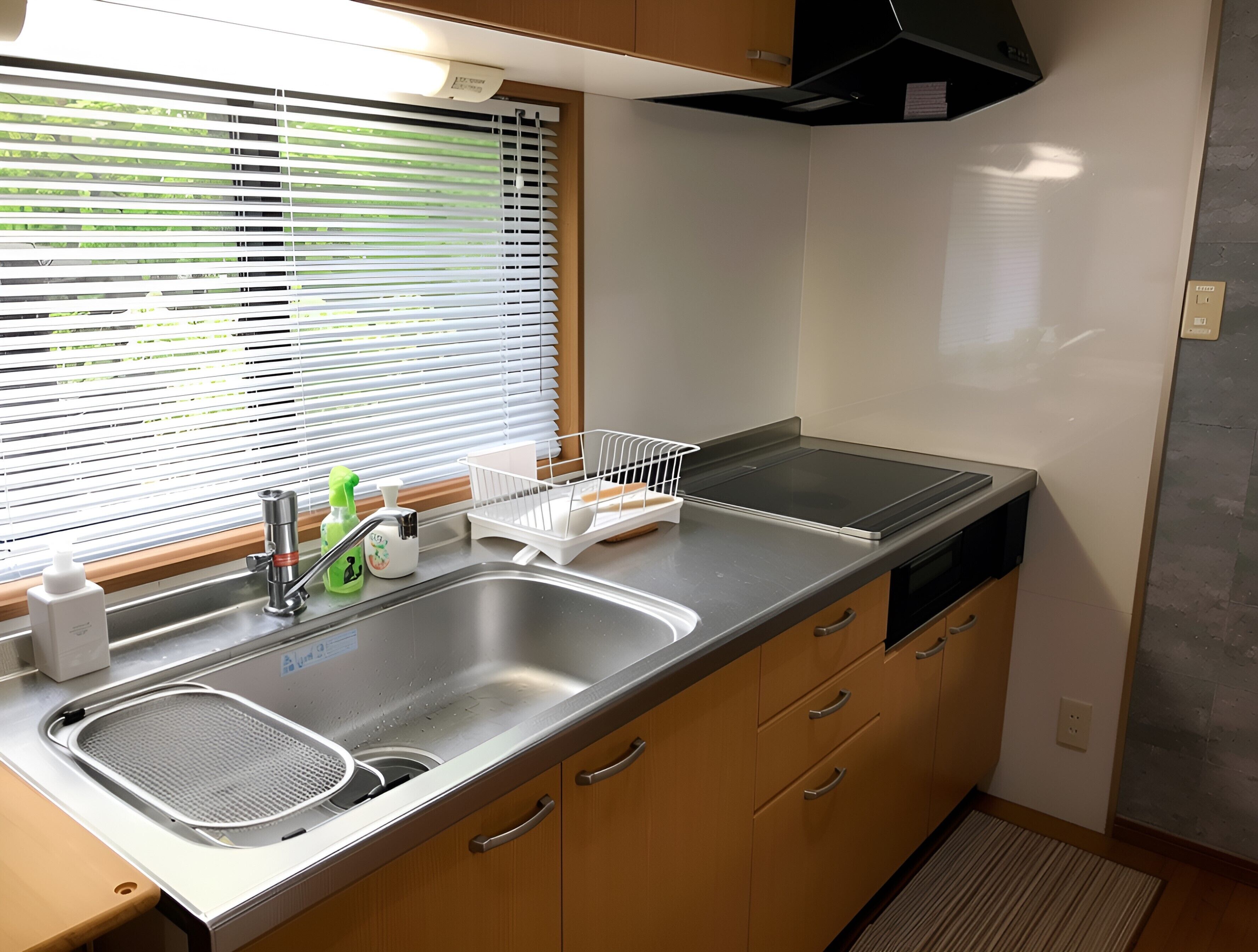 A compact kitchen with a sink, dish rack, and stove.