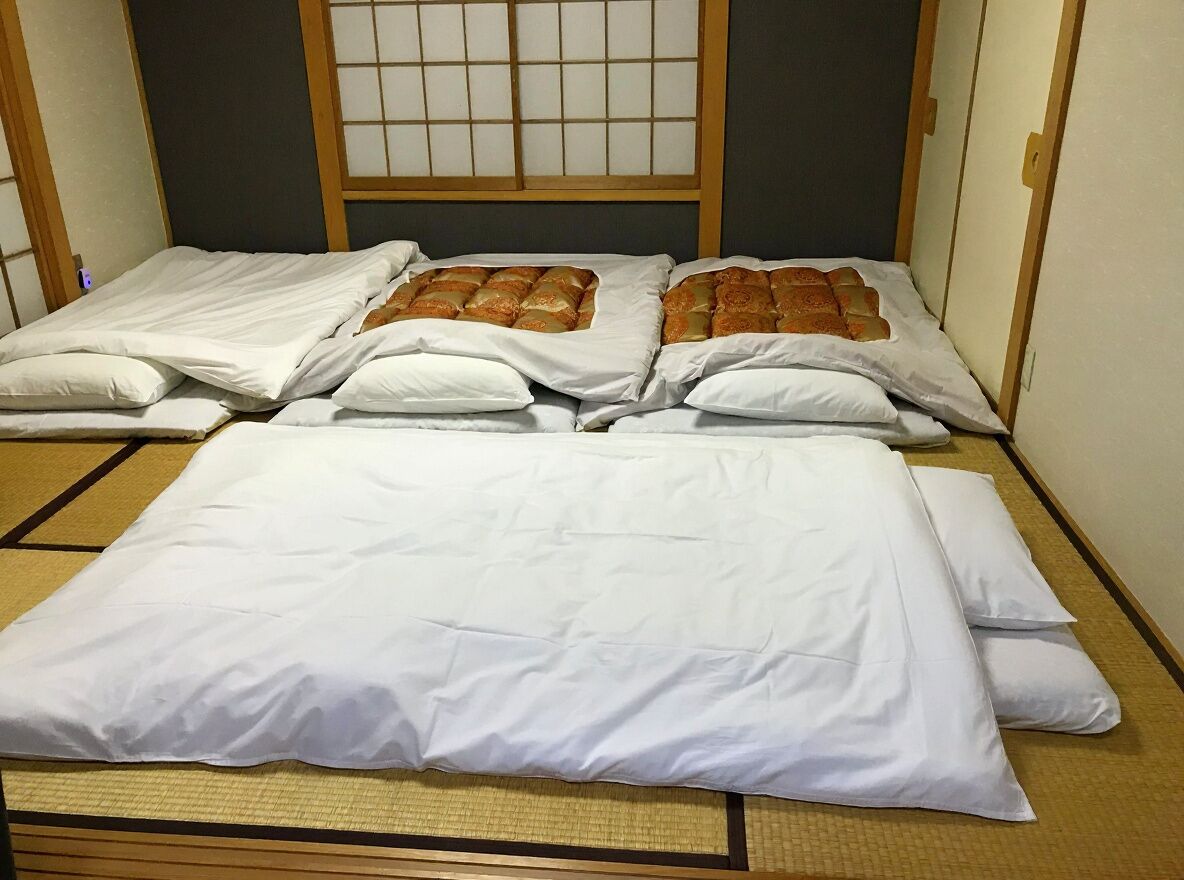 Una habitación japonesa tradicional con suelo de tatami, un bajo marco de cama de madera y una pantalla shoji.