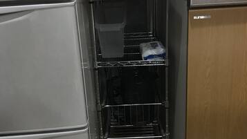 Ett kök med ett vitt kylskåp, en induktionshäll i rostfritt stål och ett träskåp.
