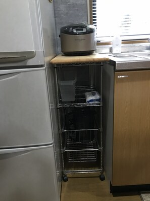 A kitchen with a white refrigerator, a stainless steel induction cooktop, and a wooden cabinet.