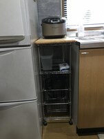 Una cocina con un refrigerador blanco, una placa de inducción de acero inoxidable y un gabinete de madera.