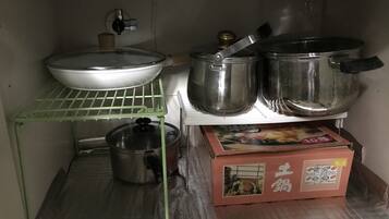A kitchen with stainless steel cookware, a green shelf, and a box with Asian characters.