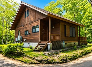 A wooden cabin with a porch, a small staircase, and a fenced yard.