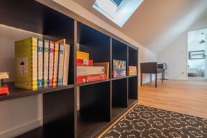 A modern interior with a bookshelf containing various items, a patterned rug, and a view of a room with a chair and a desk. - Villa Les Patys (Vouvray)