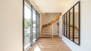 Ein modernes Interieur mit einer Holztreppe, großen Fenstern und einem klaren, minimalistischen Design.