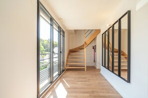 A modern interior with a wooden staircase, large windows, and a clean, minimalist design. - Villa Les Patys (Vouvray)