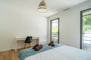 A bedroom with a bed, a desk, a chair, a window, and a hanging light fixture. - Villa Les Patys (Vouvray)