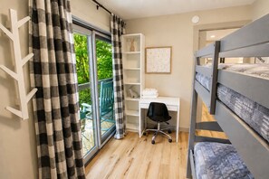 Une chambre avec un lit superposé, un bureau avec une chaise, une bibliothèque et une fenêtre avec des rideaux.