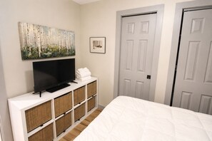 A bedroom with a bed, a television on a white console, a painting, and two doors. - Beech Mountain Getaway with Fireplace & Views (Beech Mountain)