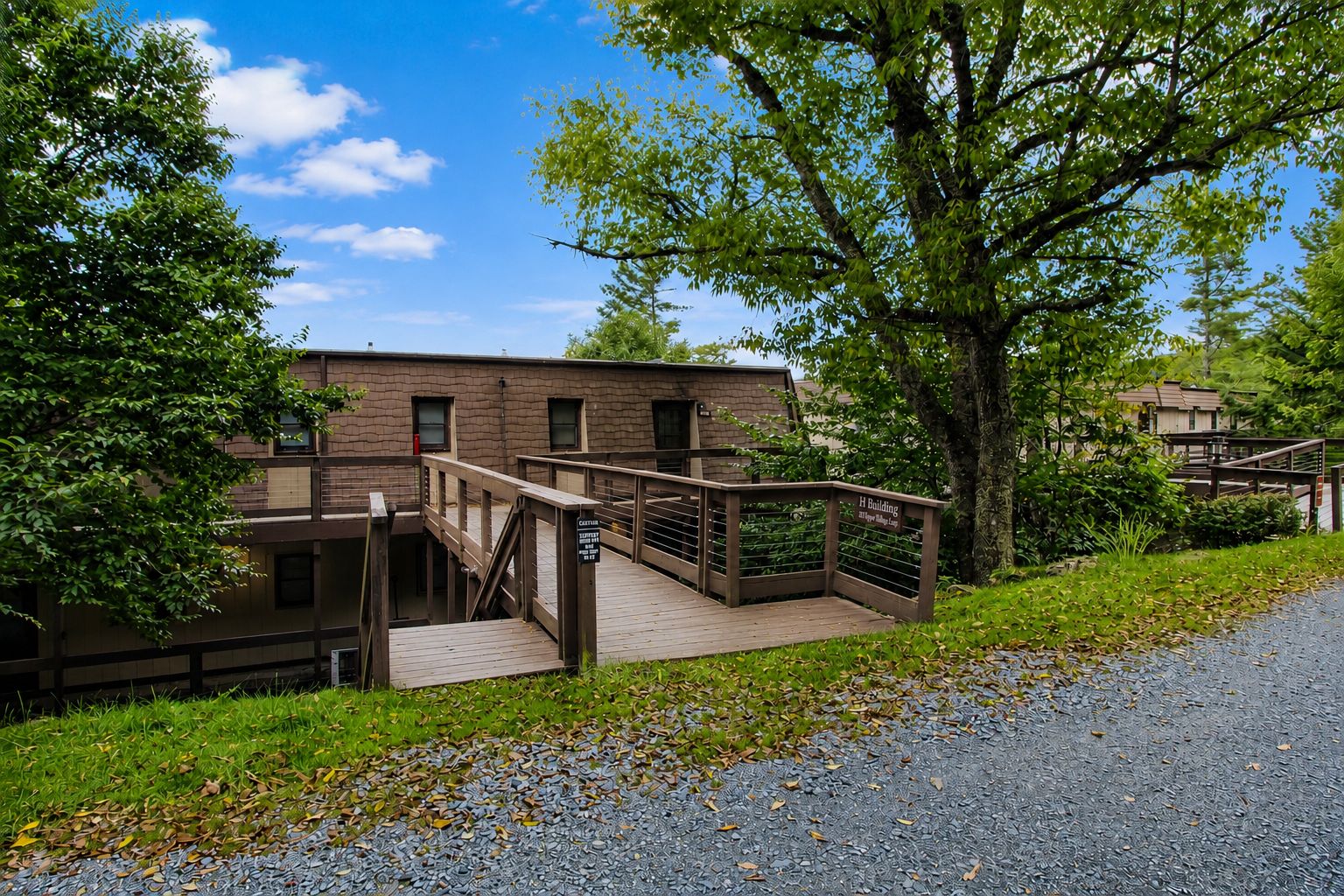 A building with a wooden deck and stairs leading to a gated entrance.