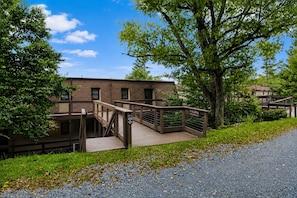 A building with a wooden deck and stairs leading to a gated entrance. - Beech Mountain Getaway with Fireplace & Views (Beech Mountain)