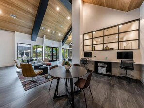 Un intérieur moderne avec une table ronde, des chaises, une bibliothèque et un bureau avec un ordinateur.