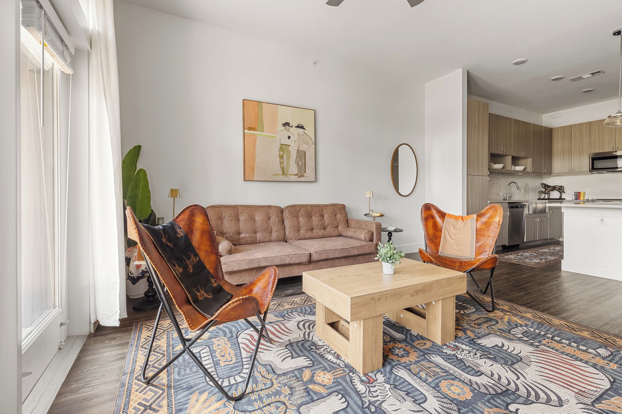 Una sala de estar moderna con un sofá, dos sillones de cuero, una mesa de centro y un tapiz estampado.