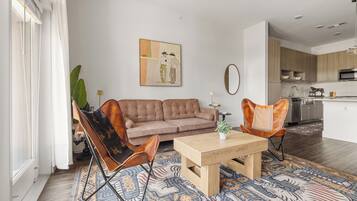 Una sala de estar moderna con un sofá, dos sillones de cuero, una mesa de centro y un tapiz estampado.