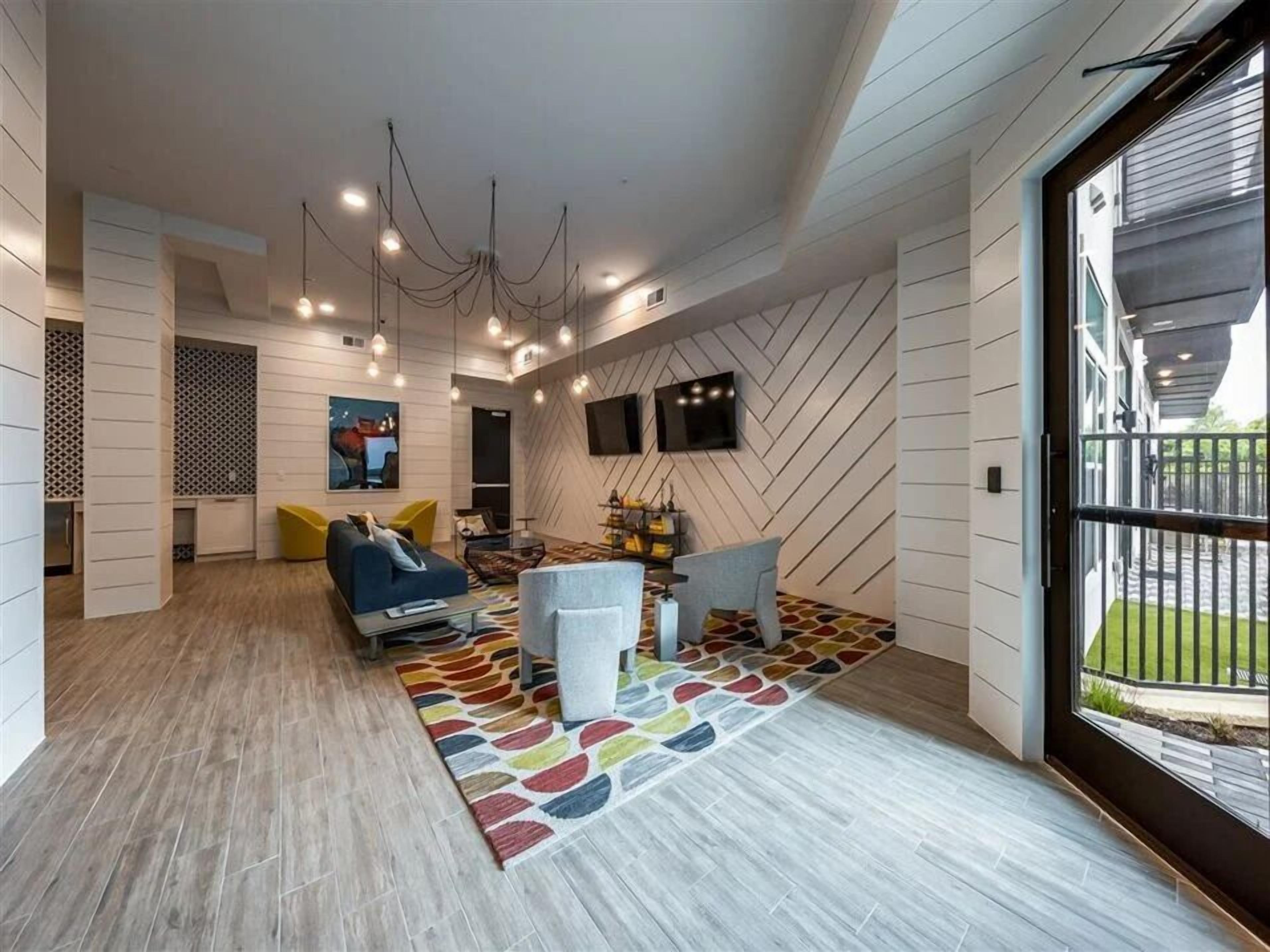 Una sala de estar moderna con un sofá, sillas, un televisor y una alfombra estampada.
