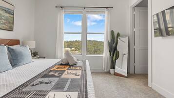 Un dormitorio con una cama grande, una ventana con vistas, una puerta y una planta.