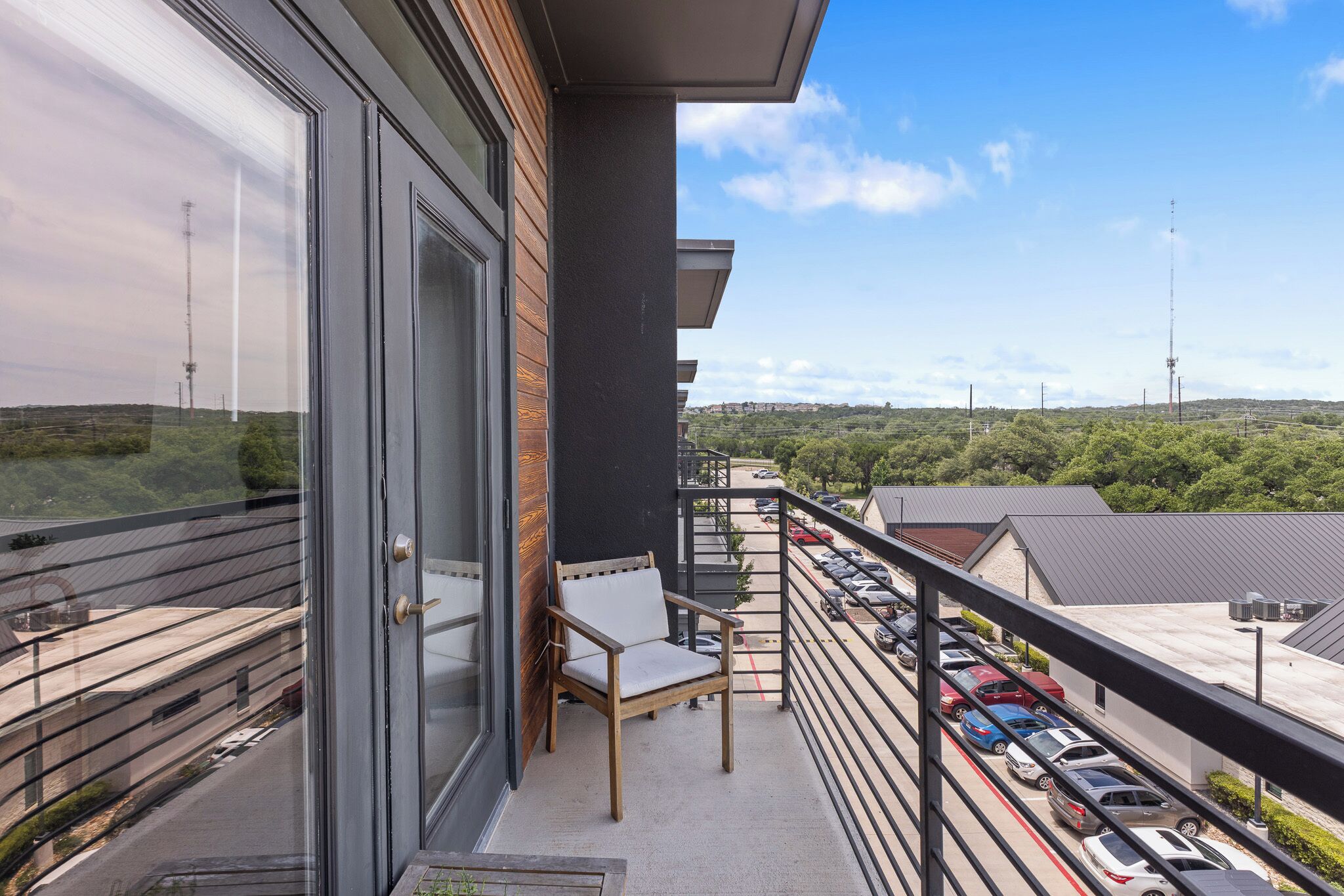 Un balcon donnant sur un parking et un paysage lointain.