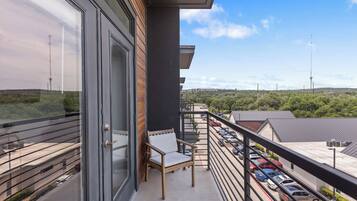 Un balcon donnant sur un parking et un paysage lointain.