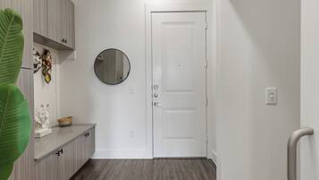 A hallway with a white door, a round mirror, and a plant.