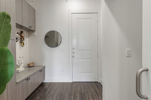 A hallway with a white door, a round mirror, and a plant.