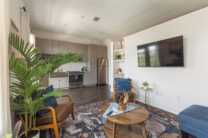 Una sala de estar moderna con un sofá, una mesa de centro y un televisor montado en la pared.