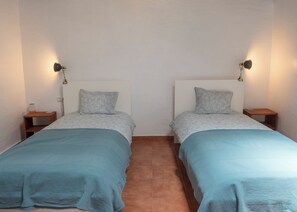 A twin room with two beds, each with a patterned bedspread and pillows, flanked by bedside tables with lamps.