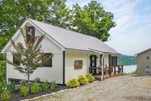 Ein Bungalow mit Veranda, umgeben von einem Schotterweg und verschiedenen Pflanzen.