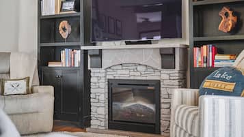 A living room with a fireplace, bookshelves, a television, and a couch.
