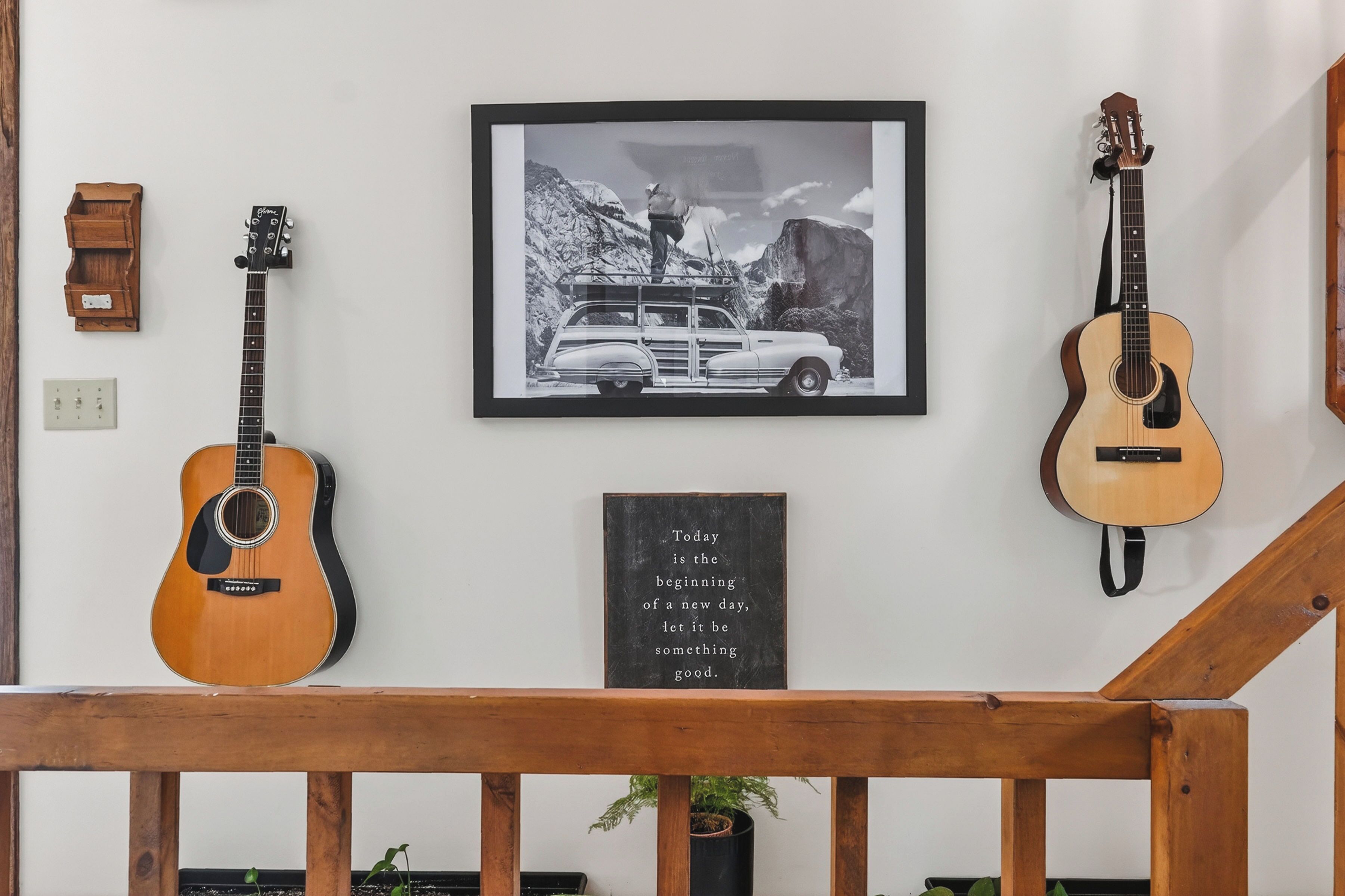 Un mur orné d’une photographie encadrée, de deux guitares, d’une petite armoire en bois et d’une citation inspirante.