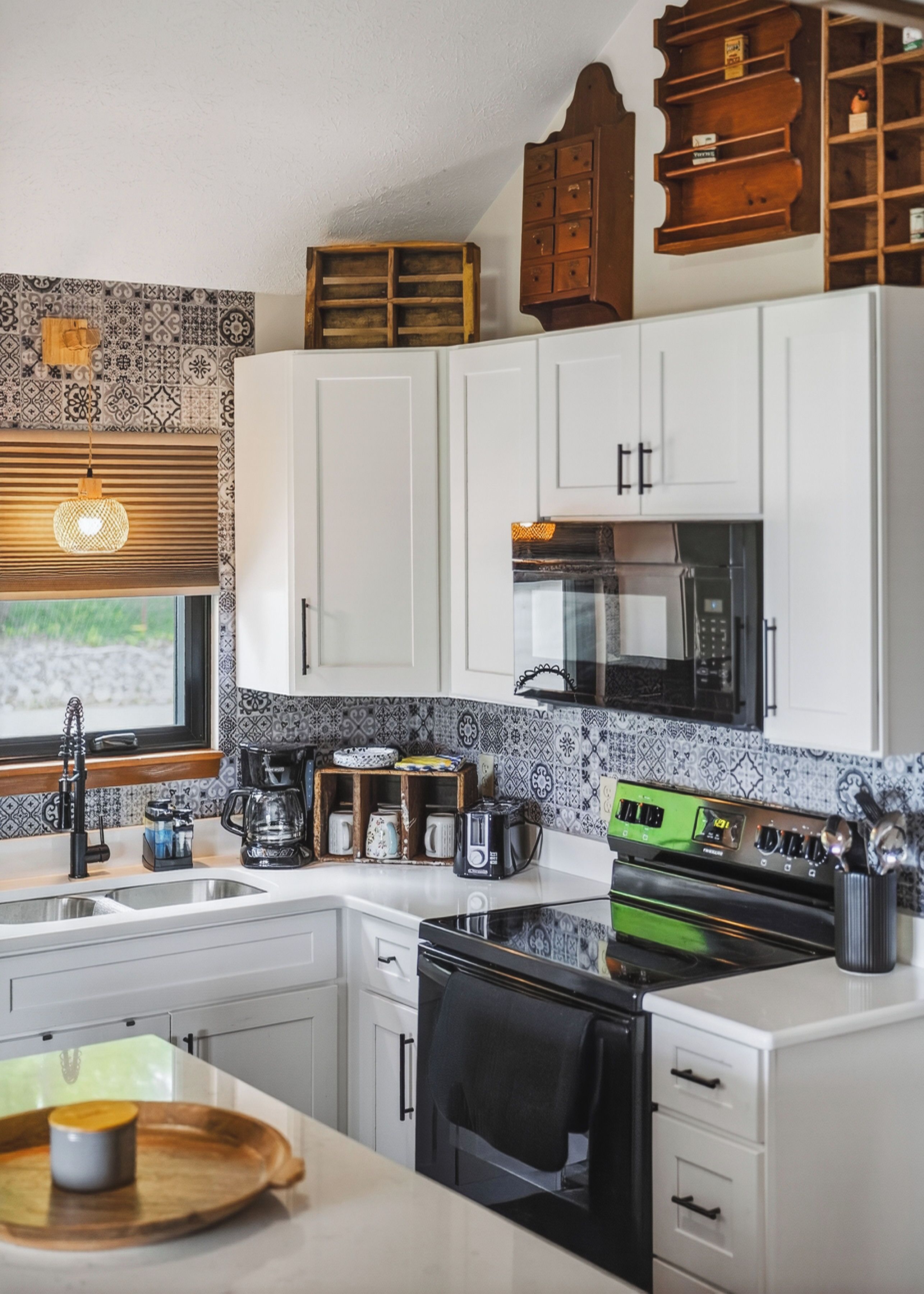 A kitchen with white cabinets, a microwave, a stove, and a coffee maker.