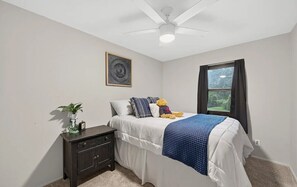 A bedroom with a bed, a nightstand, a ceiling fan, a window with curtains, and a wall-mounted picture. - Luxury Living in one of St Louis' Most Sought-After Neighborhoods (St. Louis)