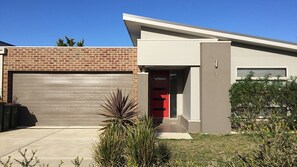 Ein modernes, zweistöckiges Haus mit Garage, rotem Eingang und Ziegelaußenwand.