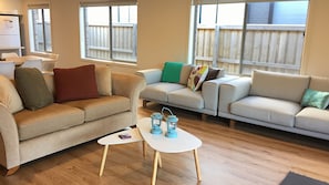 A living room with two sofas, a small table, and a refrigerator. - Lakeside - Point Lonsdale (POINT LONSDALE)