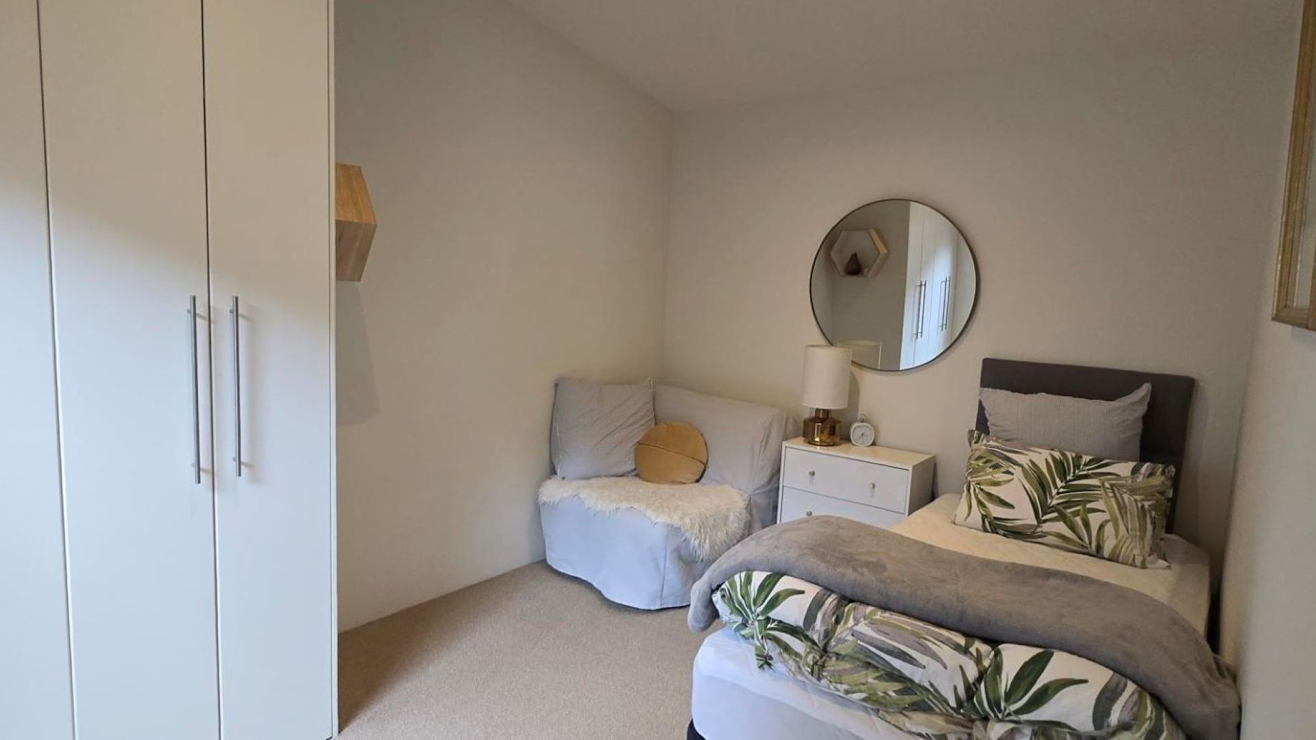 A bedroom with a bed, bedside table, lamp, and a wardrobe.