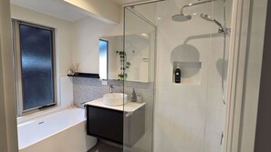 Une salle de bain moderne avec une douche à parois de verre, une baignoire blanche et un meuble-lavabo avec un évier et un miroir.