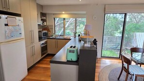 Eine moderne Küche mit einer großen Kücheninsel, einer Mikrowelle und einem Toaster. Ein Fenster bietet Blick ins Freie.