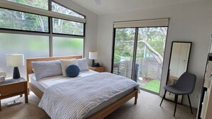 A bedroom with a bed, two bedside tables, a chair, a wardrobe, and a sliding glass door leading to a balcony. - Moonah Delight - Point Lonsdale (Point Lonsdale)