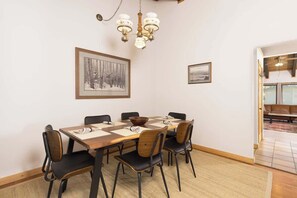 Ein Essbereich mit Holztisch, schwarzen Stühlen, einer Pendelleuchte und gerahmten Kunstwerken an den Wänden.