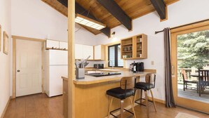 Cozinha com ilha de madeira, banquetas e vista para um deck externo.