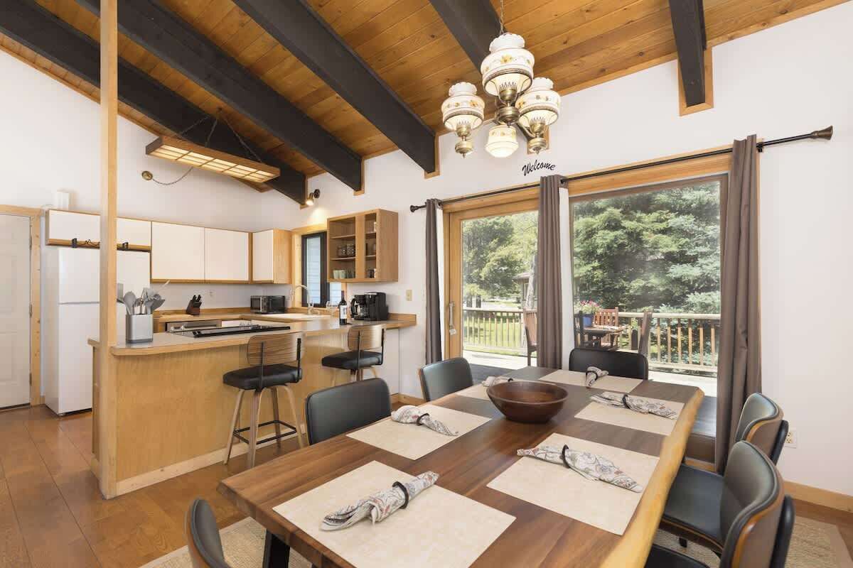 Une cuisine moderne avec des meubles en bois, un îlot central et un coin repas comprenant une grande table et des chaises.