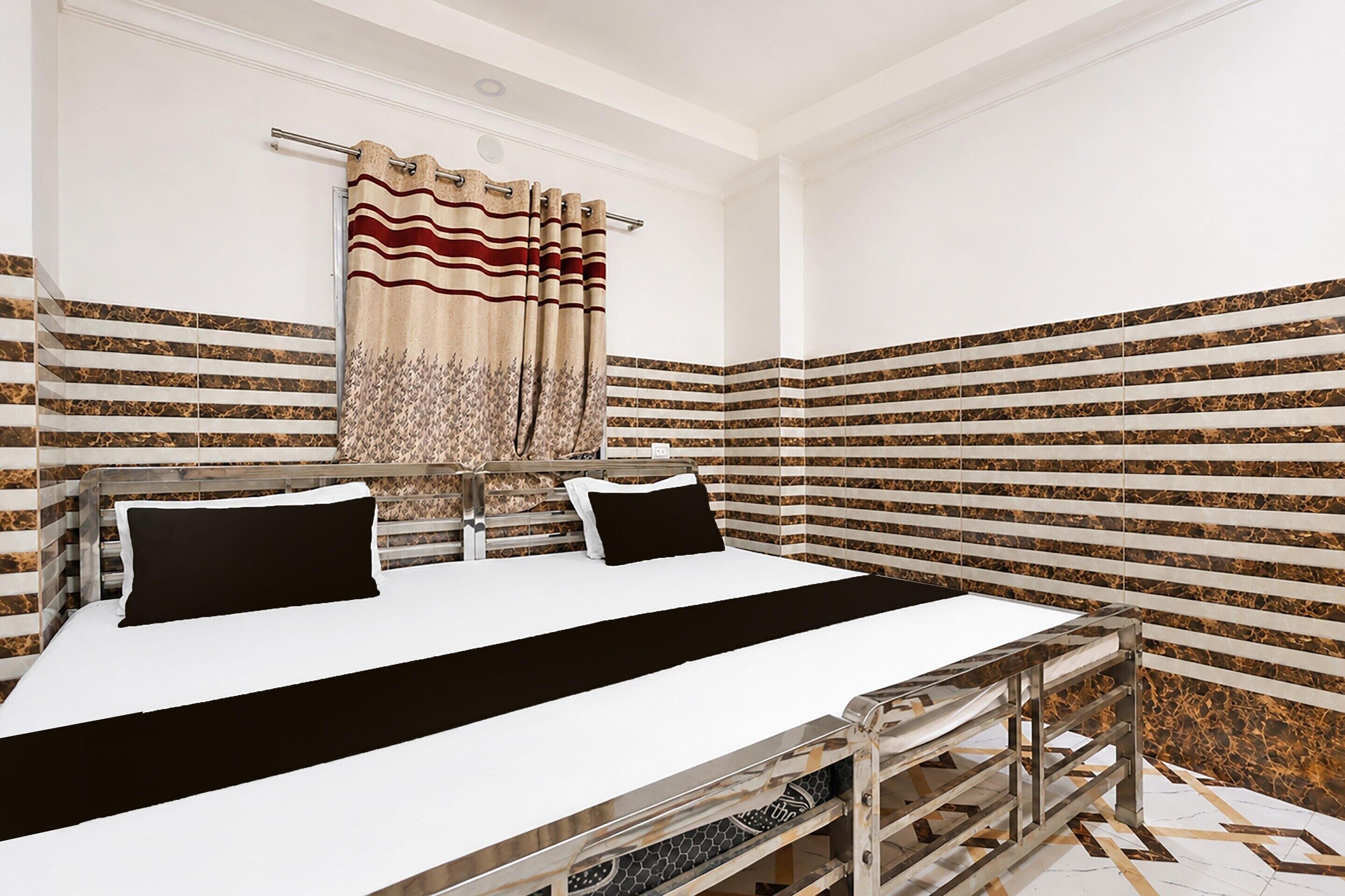 A hotel room with a bed, a bedside table, and a window with curtains.