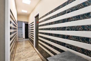 A hallway with a marble floor, striped wall tiles, and a door with the number 09. - Deluxe With Twin Bed Ayush Villa (Kolkata)