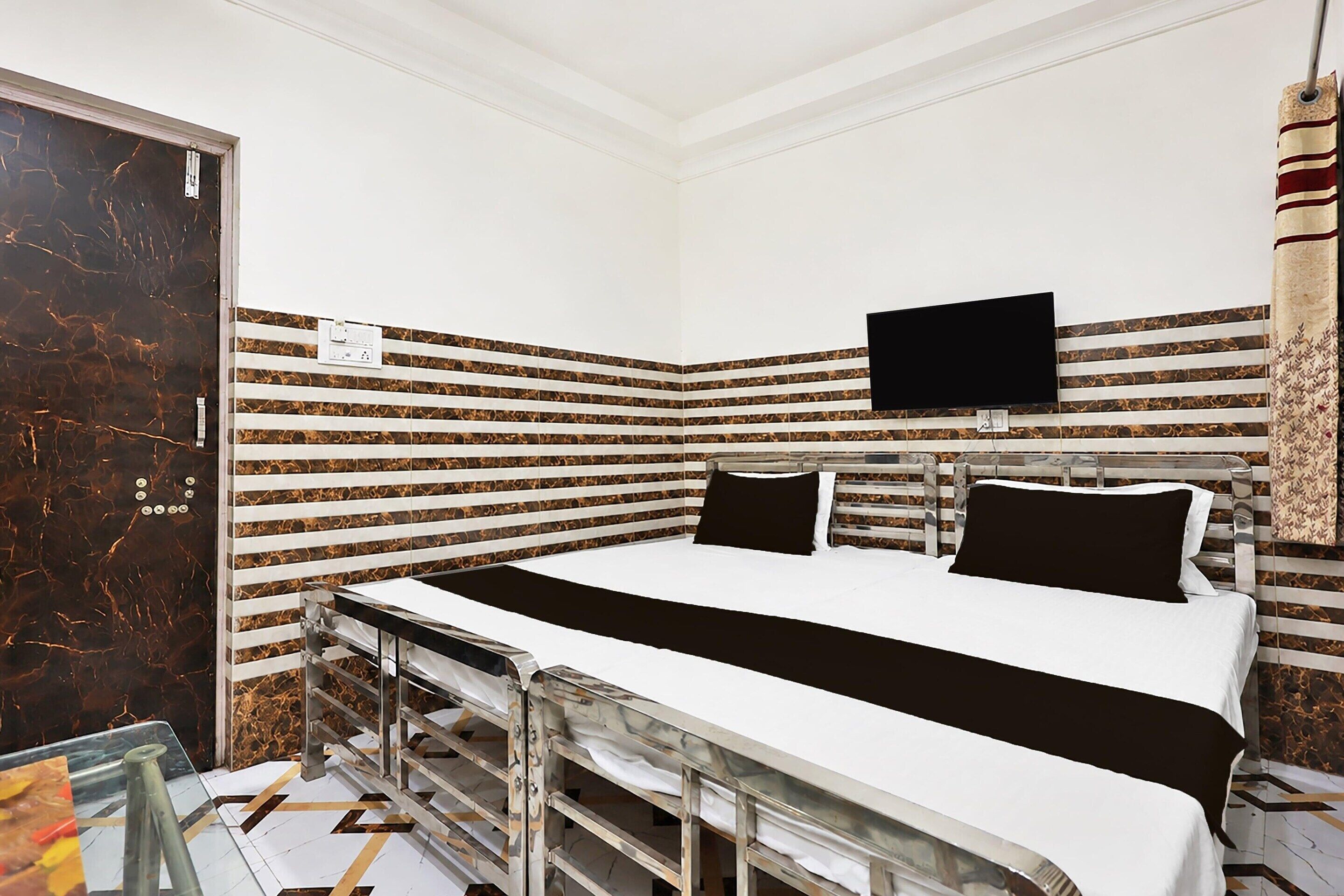 Een hotelkamer met een bed, een aan de muur bevestigde televisie en een kamer met een patroon op de muur.