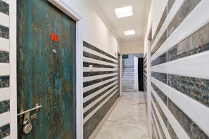A hallway with a blue door marked with the number 10, white railings, and a tiled floor. - Deluxe With Twin Bed Ayush Villa (Kolkata)