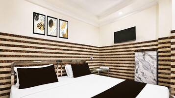 A hotel room with a bed, a TV, and a bathroom with a marble wall.